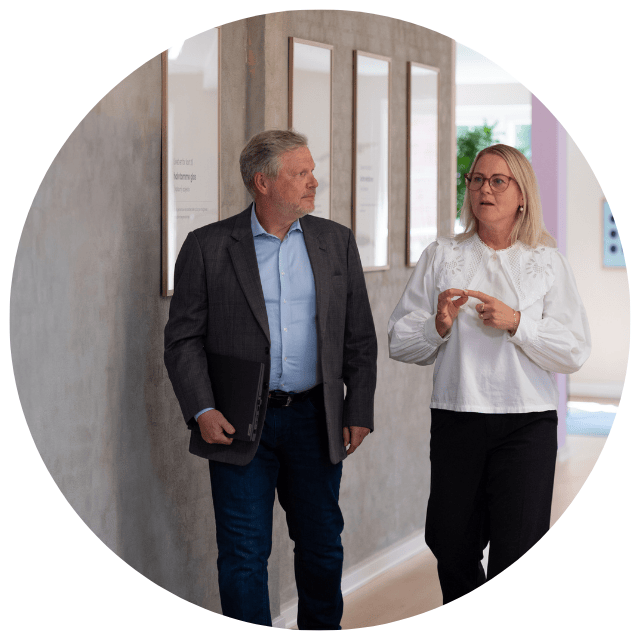 Two business professionals, a man and a woman, from KOLLAB walking down the corridor discussing their recruiting strategy.